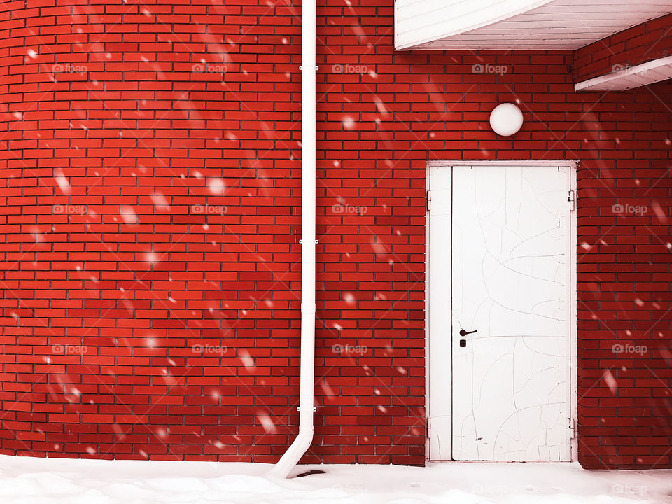 White snow on red brick wall with white door background 