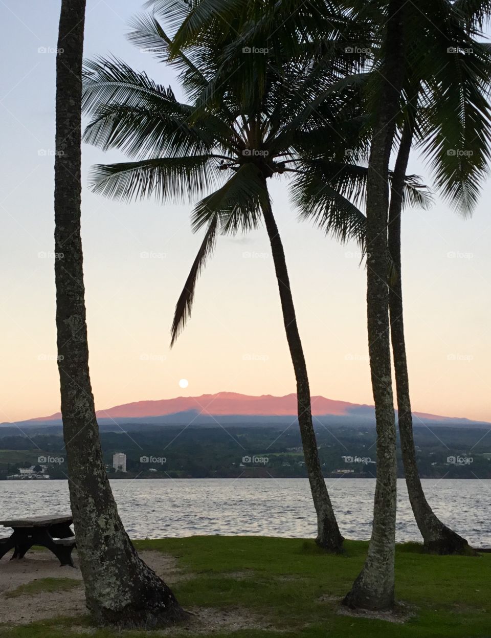 Moon receding as the sun illuminates the volcano