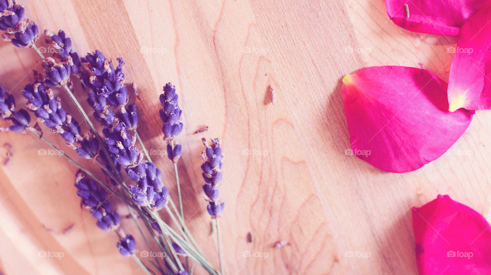 Flat lay of fresh lavender flowers and red rose petals on wood background aromatic edible flower ingredients or beauty fragrance and skincare ingredient summer flower background with room for copy 