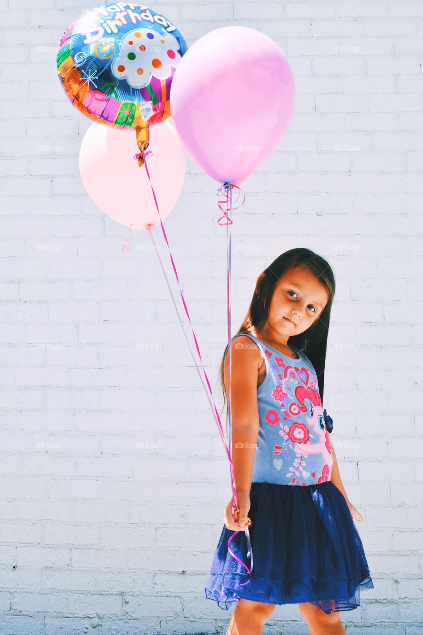 Little girl holding birthday balloons in hand