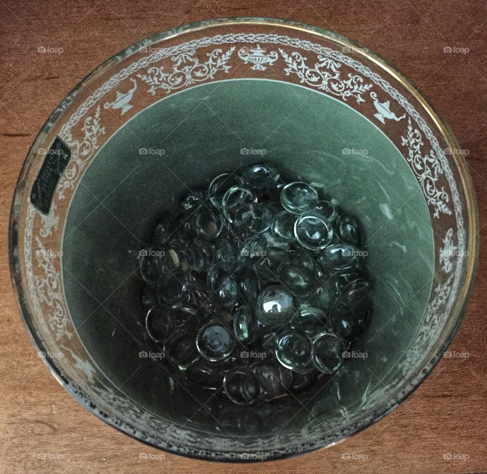 A decorative green glass full of blue glass beads. This is a downward shot into the cup that shows its contents.