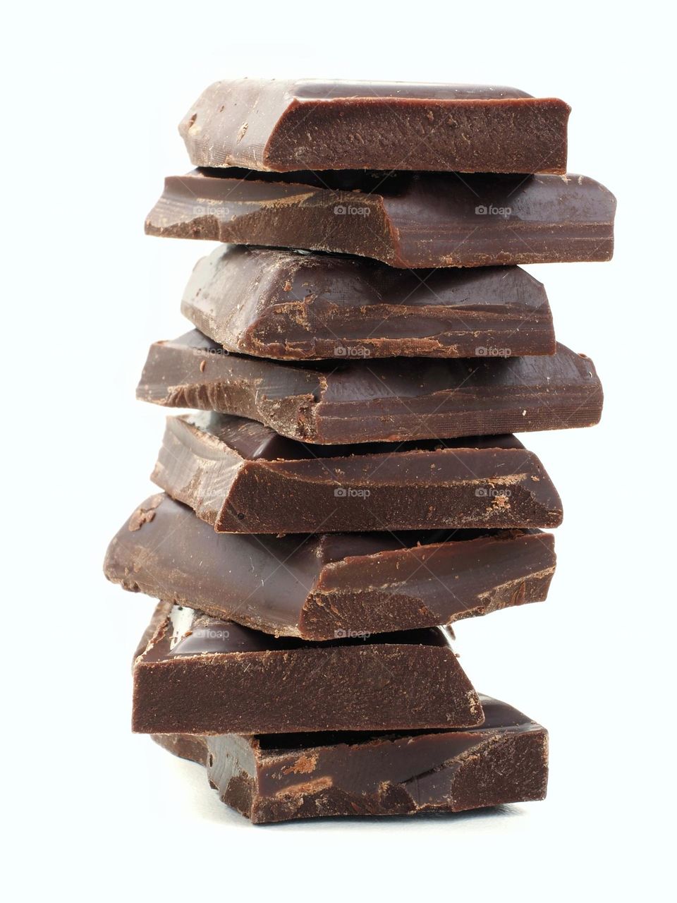 a stack of dark chocolate pieces are on a White background