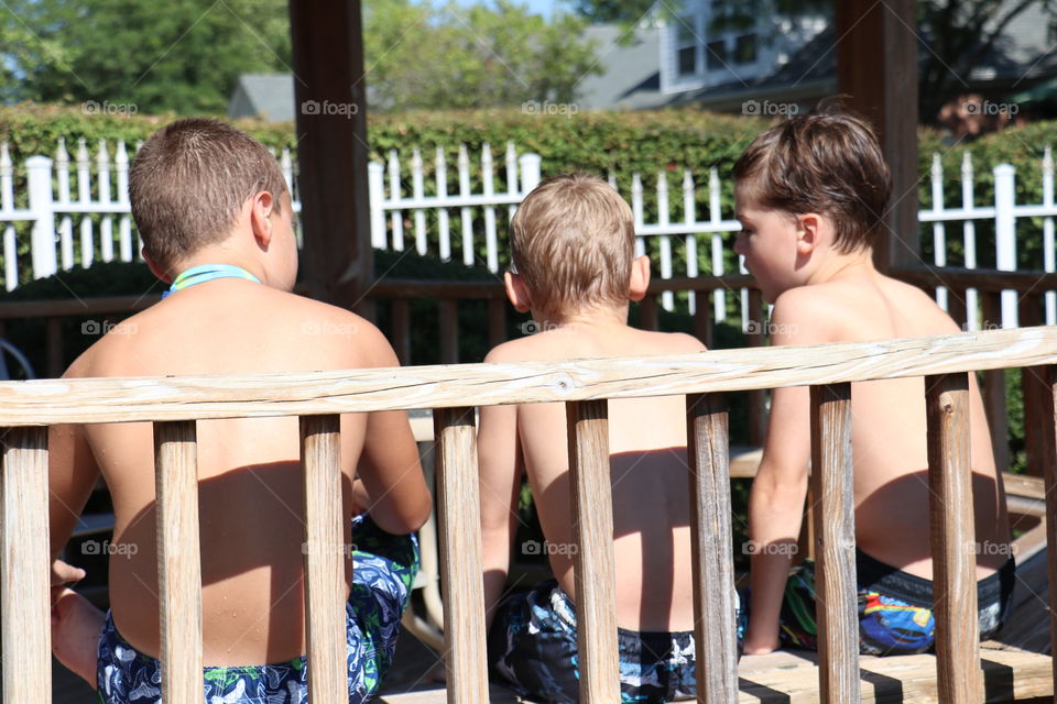 Rear view of children sitting on wooden bench