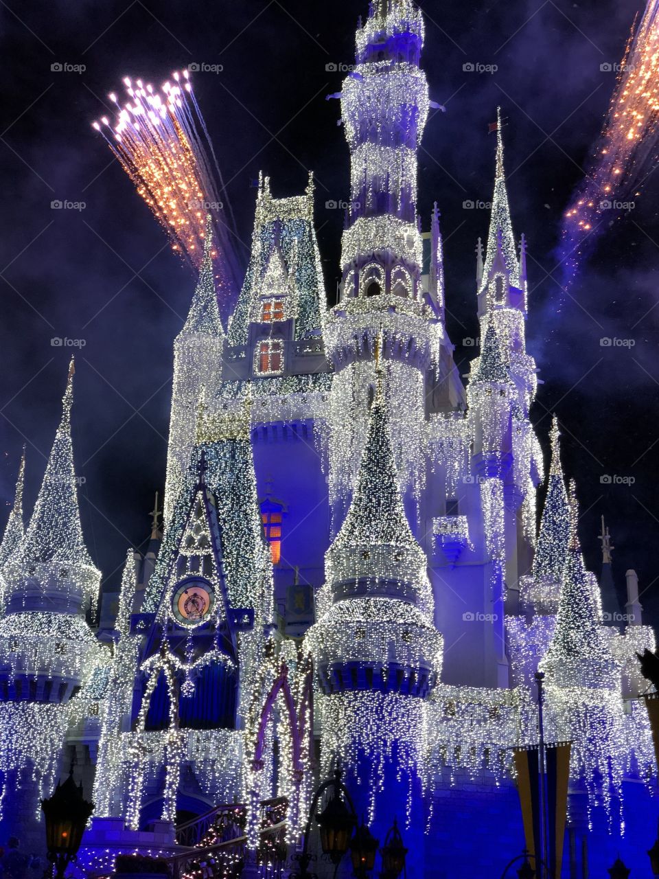 Disney world castle with icy lights and fireworks at night