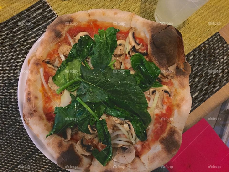 Fresh vegetarian Italian pizza in Mexico,  covered with cheese, spinach, sweet onions, and tomato sauce
