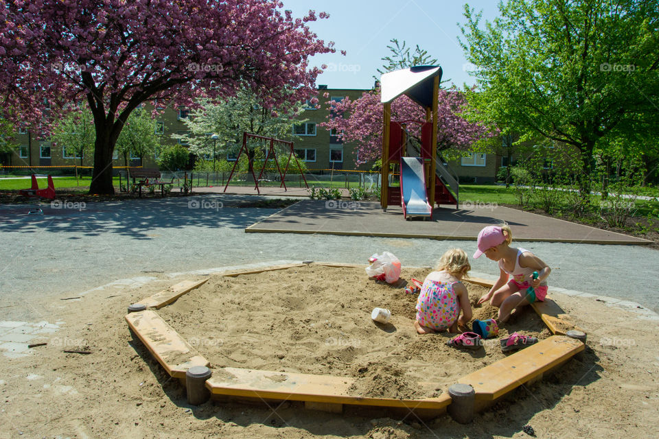 Two sisters is playing at a playground.