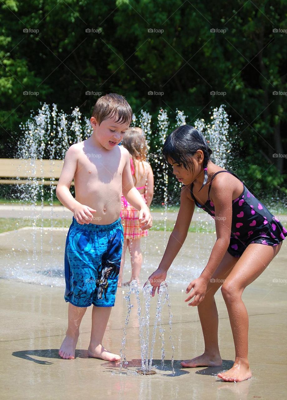 Boy and girl playing at a splash pad