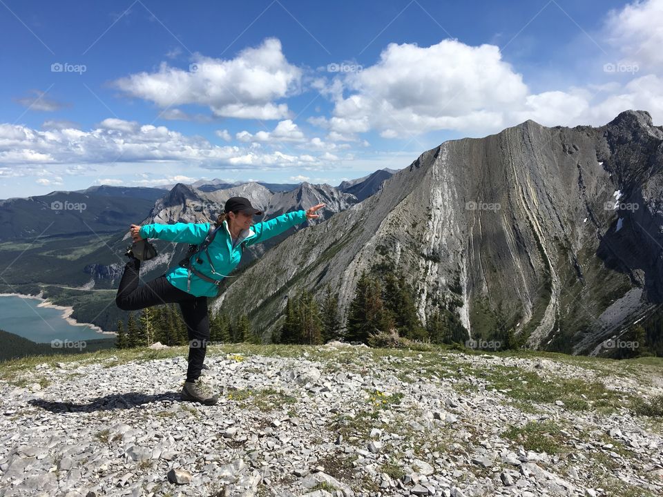 Woman hiker posing on one foot at mountain