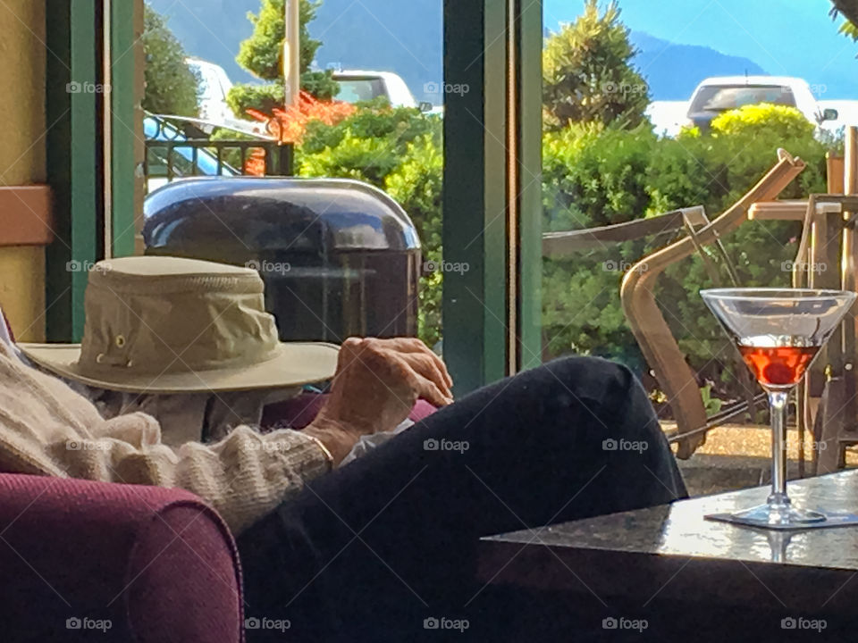 Elderly man relaxing in hotel resort bar by a window with a martini cocktail 