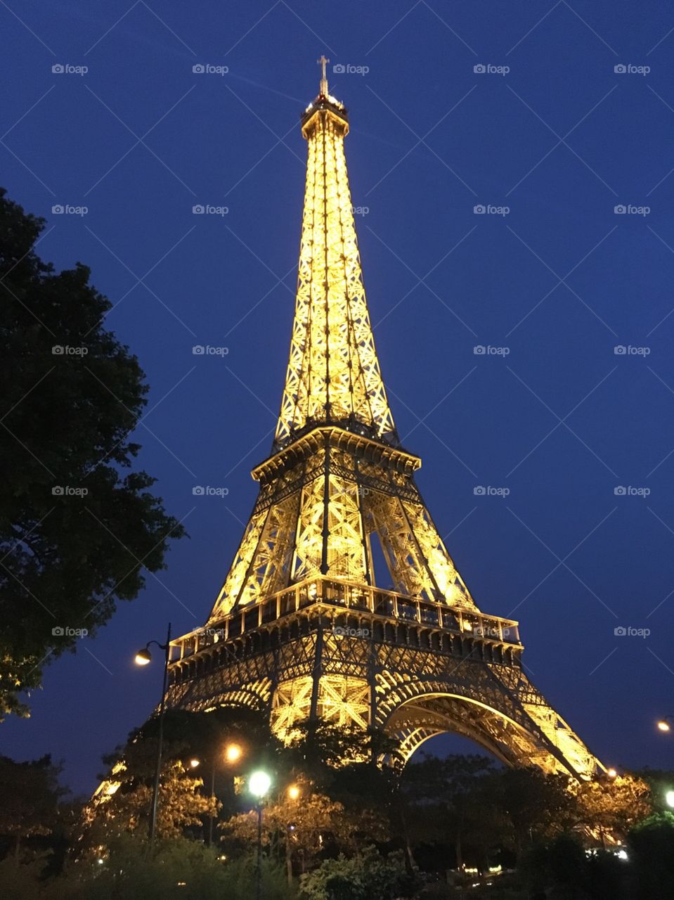 Eiffel Tower at night against blue sky. 