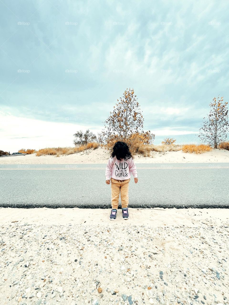 Beach landscape with road and toddler, toddler stands in front of beach road, beaches of Michigan, landscape beach photography with a smartphone, vast sky and endless beaches, empty beach in Michigan