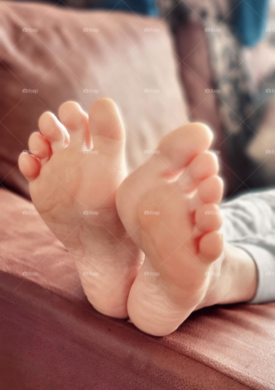 Barefoot soles of feet with toes spread lying on a sofa