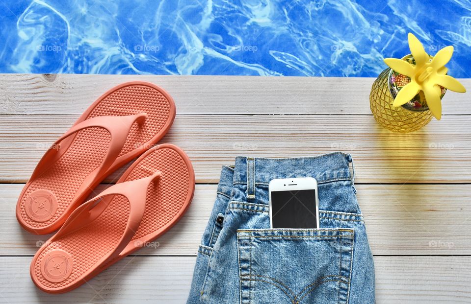 Electronics, flat lay of smart phone in jean pocket beside a pool