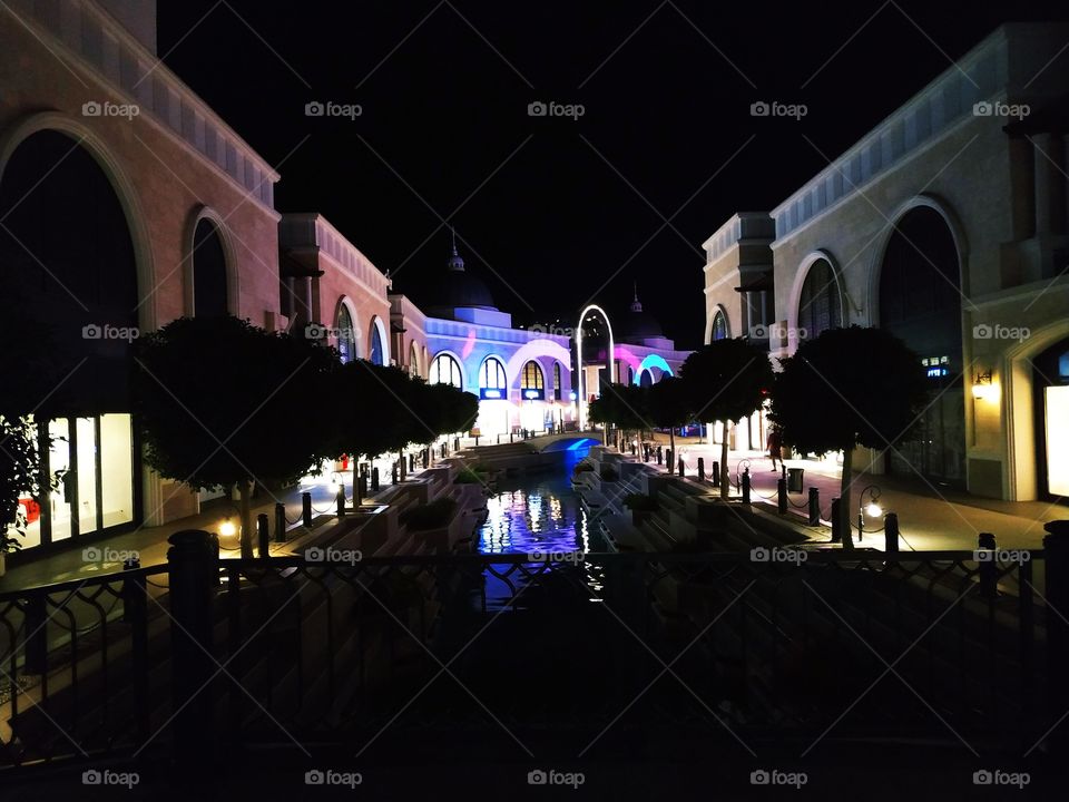 A beautiful view from the bridge to the avenue with creek, trees and shops.