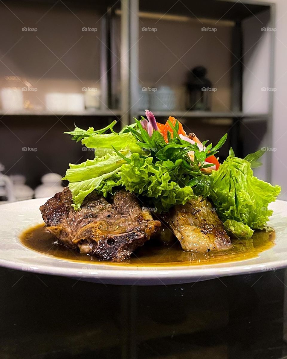 Cooked Lamb chop being served with black pepper sauce.