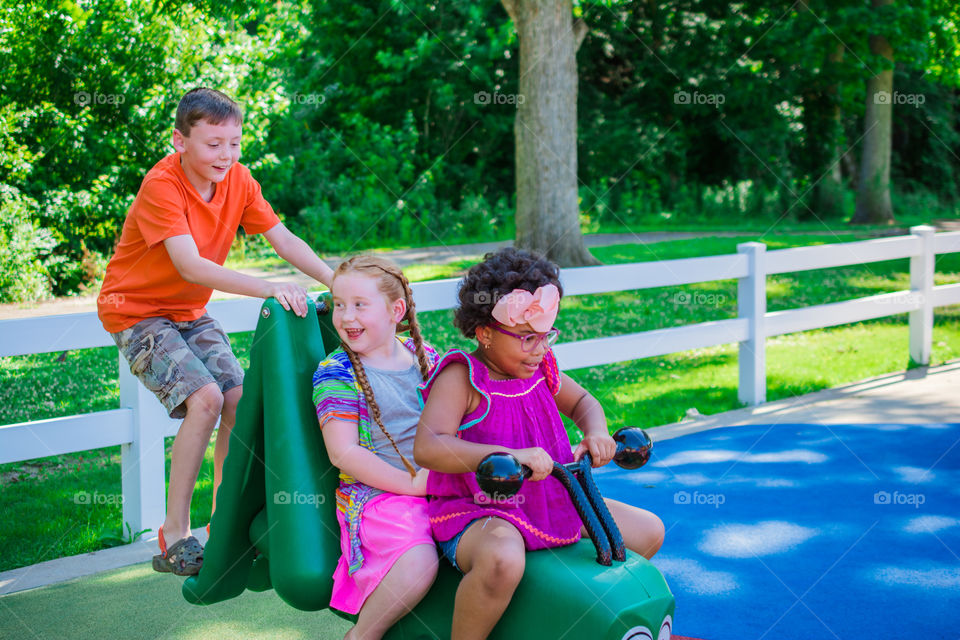 Three Kids at the Playground on the Caterpillar Having Fun