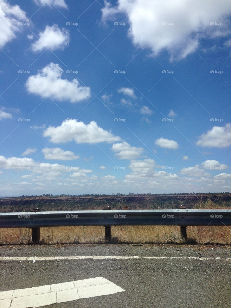 High up clouds off the freeway on a bright blue sky overlooking a canyon. Slip away in this land of floating among the clouds. 