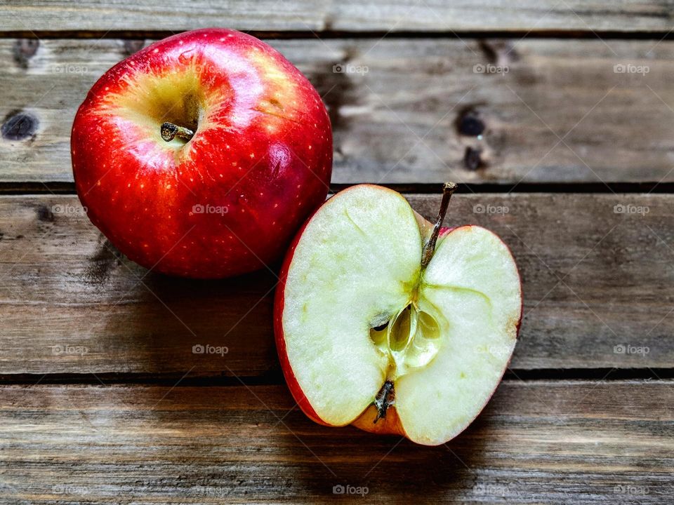 A whole apple and half an apple on a wooden background