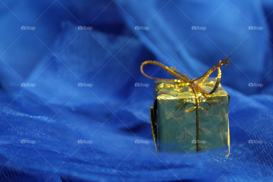 Golden Christmas gift on blue background.