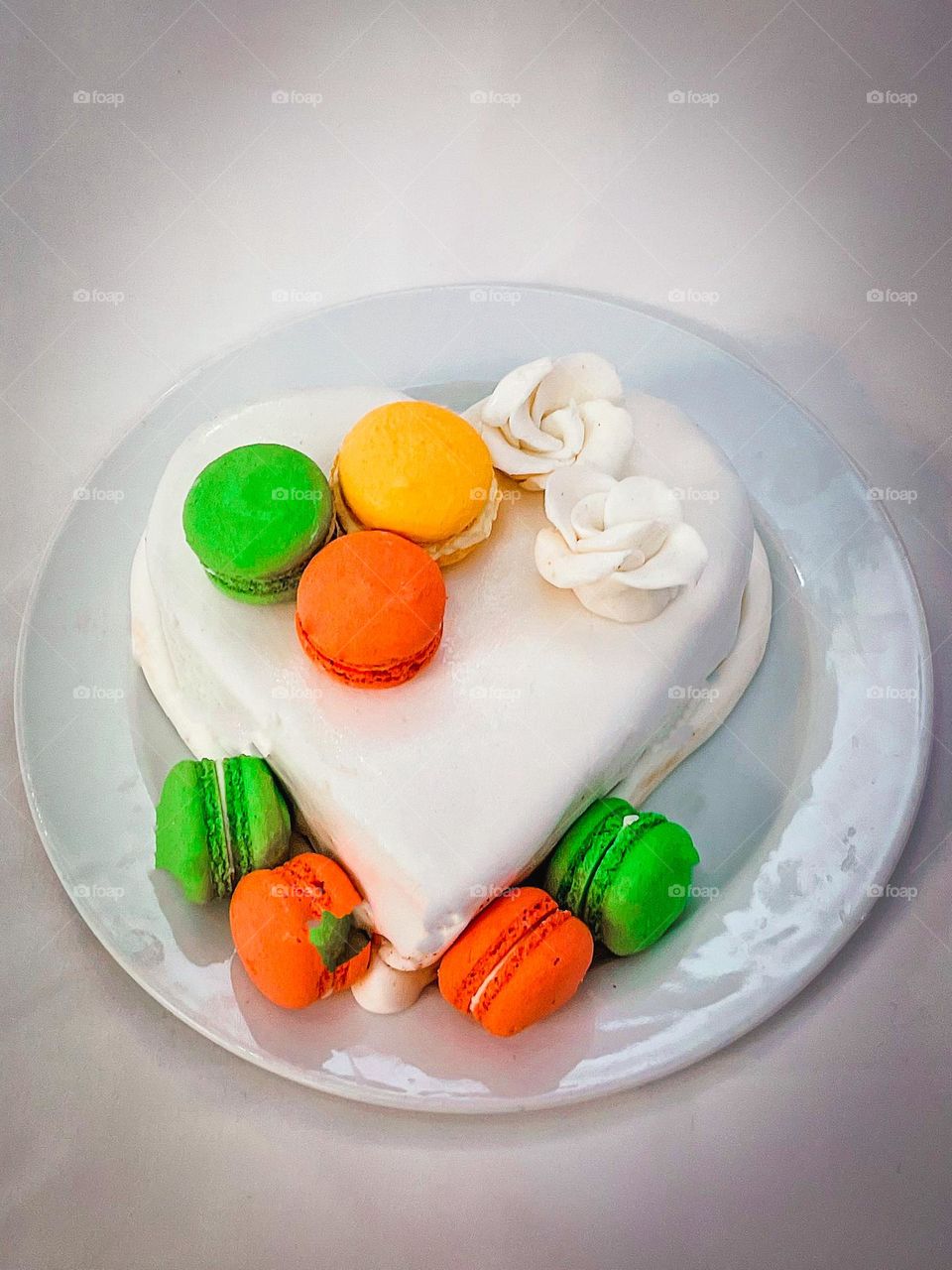 White heart shaped cake, with colourful macarons on top.