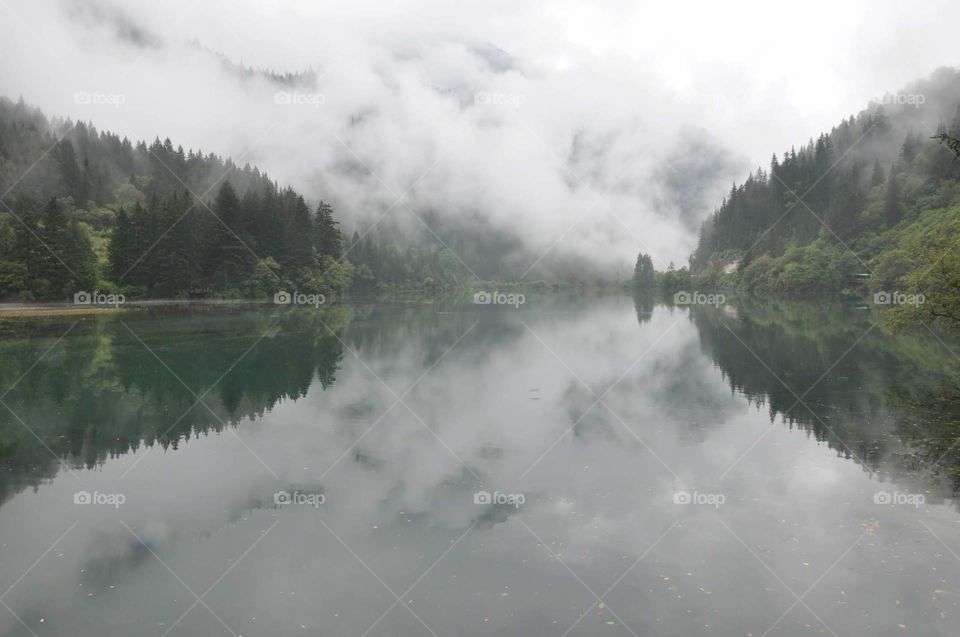 Mystical foggy clouds over a beautiful lake and forest in China