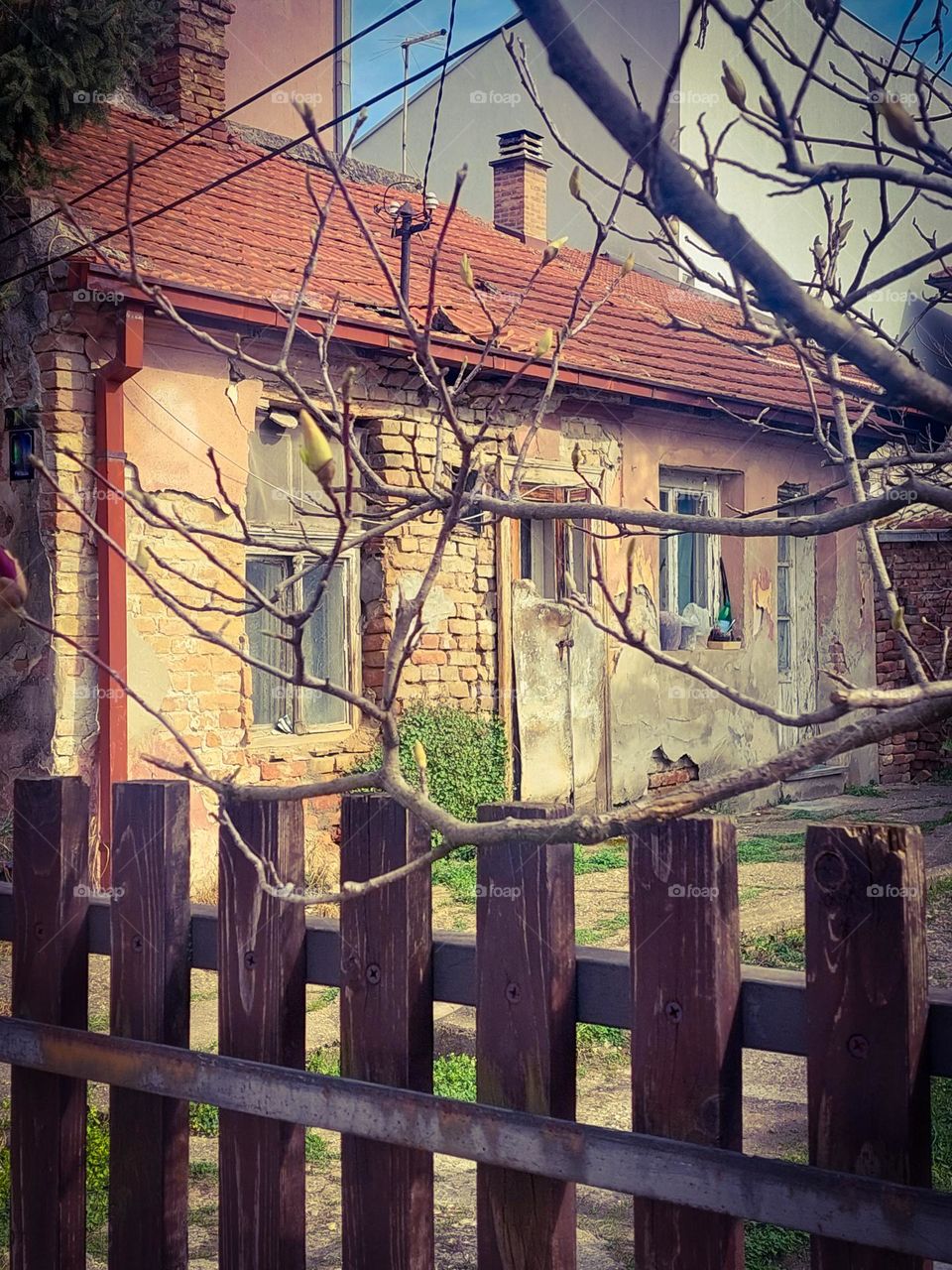 Contrast.  An old abandoned house surrounded by new buildings.  City scape