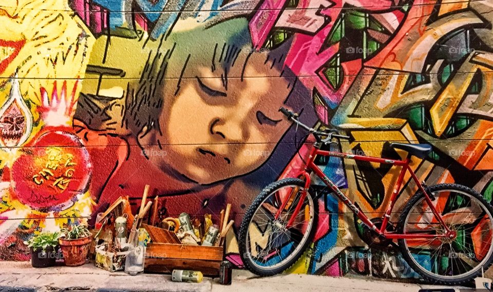 Bicycle parked in front of mural on wall