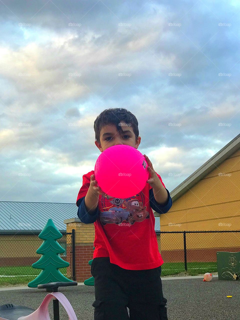 Boy playing on playground with his neon ball 