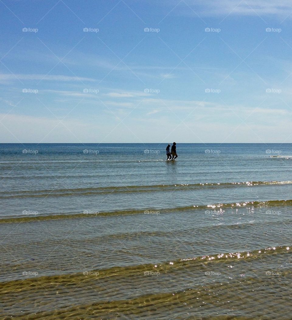 Two people walking in sea