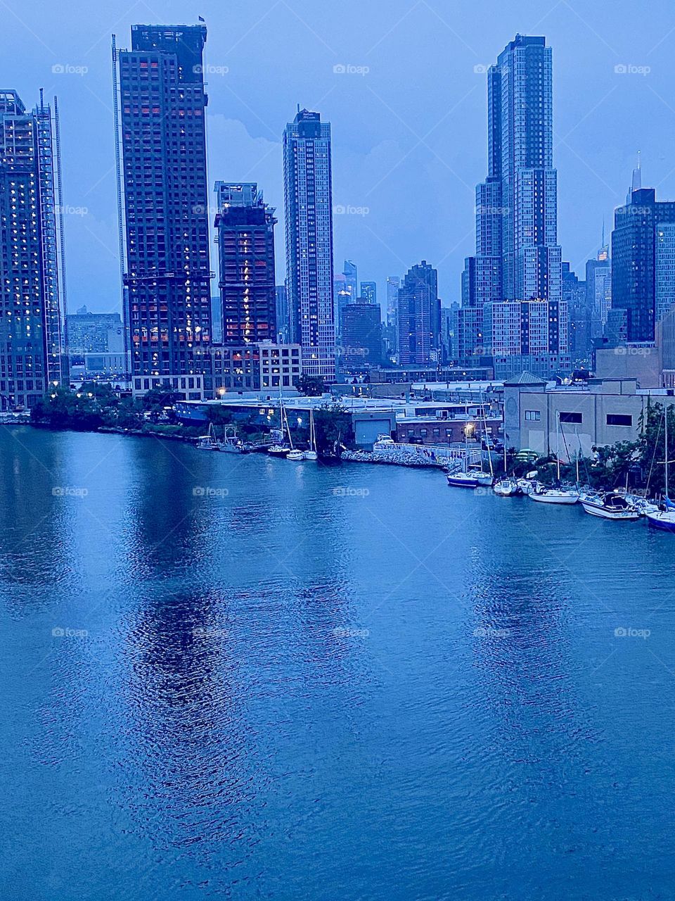 This is beautiful „Newtown Creek“ as seen from the „Pulaski Bridge“ in LIC, Queens at twilight time in September of 2023. The „East River“ has formed a large smooth mirror that the NYC cityscape is reflecting in. 2023. Hypnotic Productions