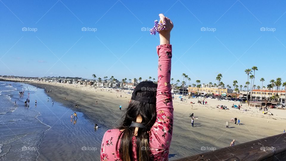 woman holding up a flower at the ocean