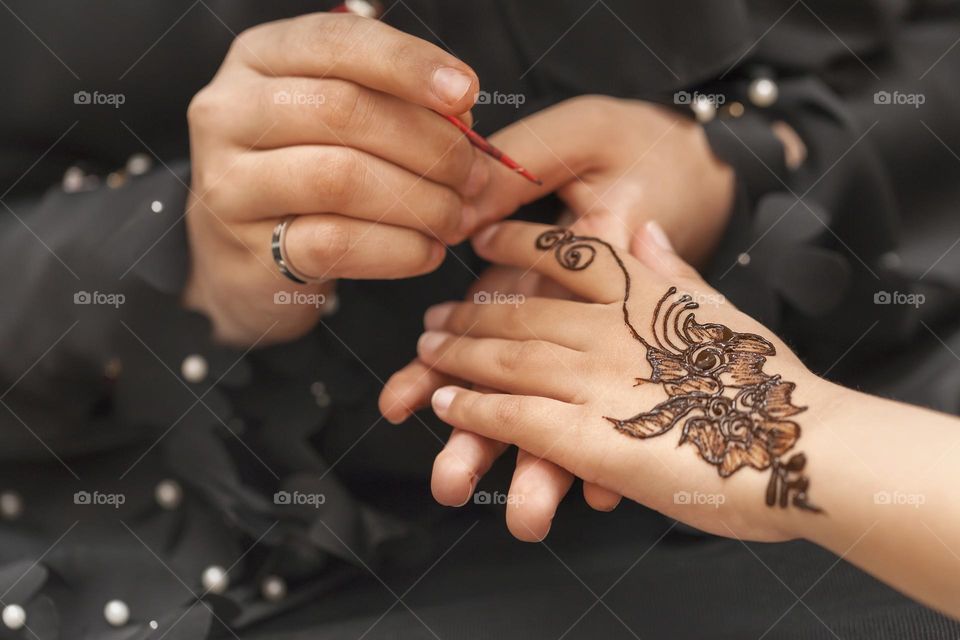 Woman applying henna on hand of a client