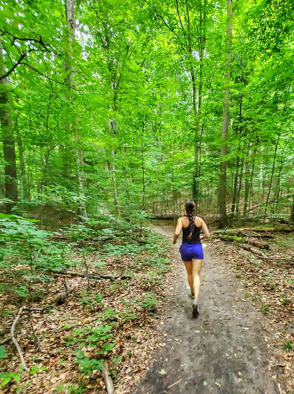 woman in shorts running on wooded trail
