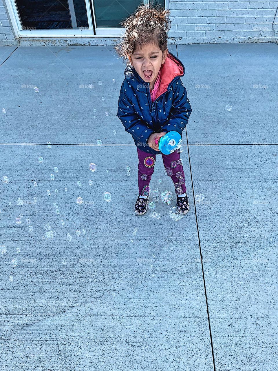 Toddler girl surrounded by bubbles, toddler screaming at bubbles, toddler blowing bubbles with bubble wand outside, circles in every day life, geometric shapes in every day life, small child having fun with bubbles, toddler screams with excitement 