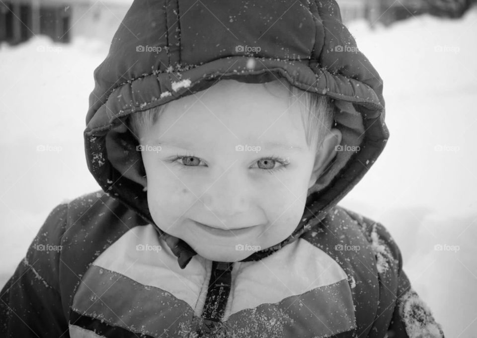 Toddler boy, in black and white, playing in the snow. 