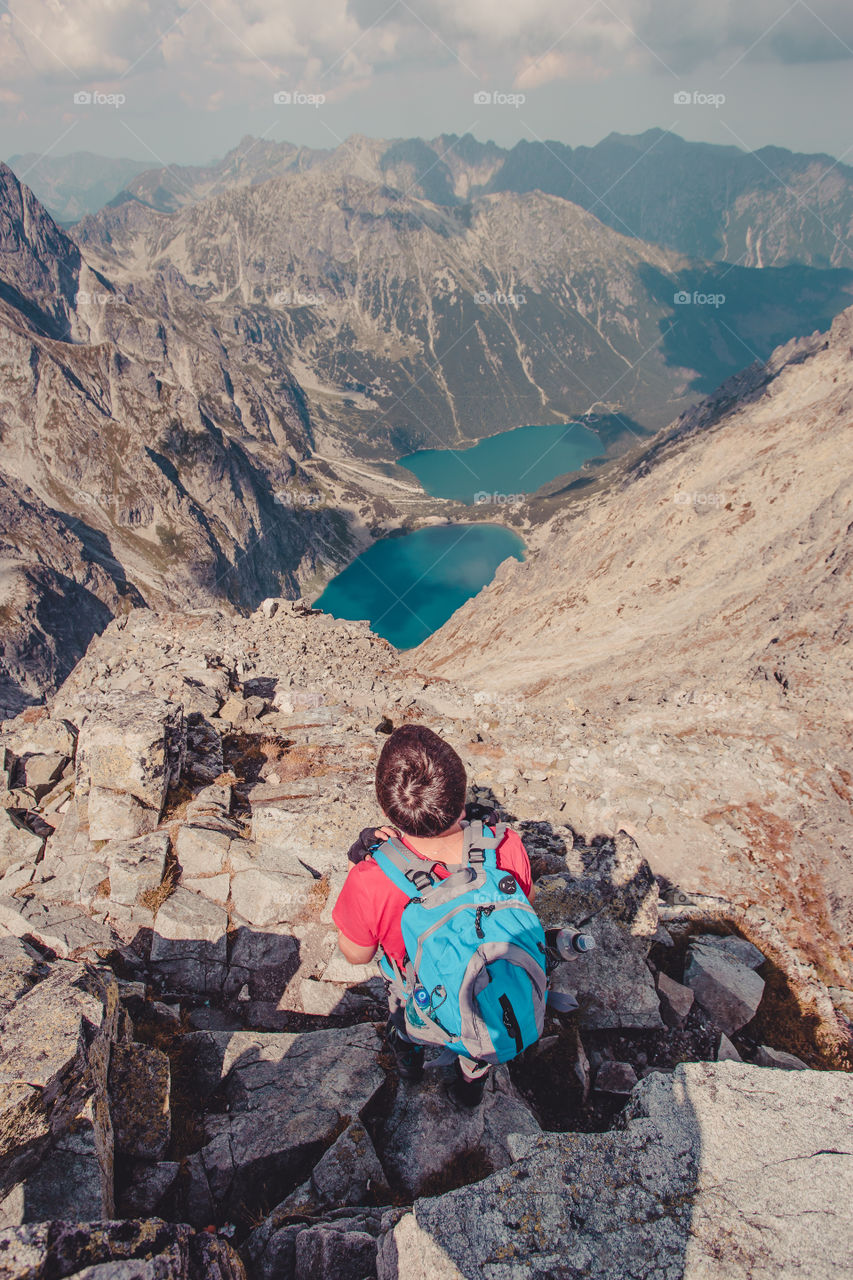 Rear view of person sitting on rock