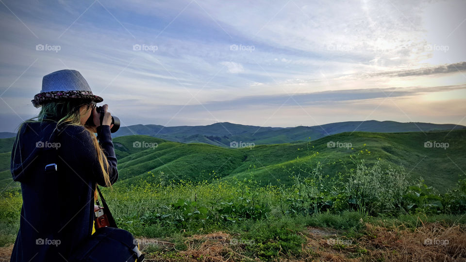 lady holding dslr camera, taking a photo of the hills in spring