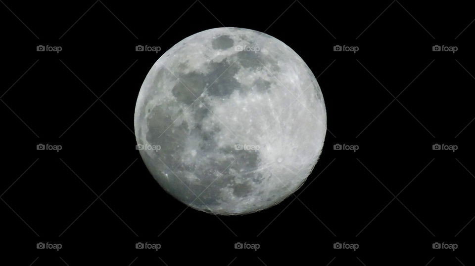 Close-up of full moon at night against blackness of outer space with craters