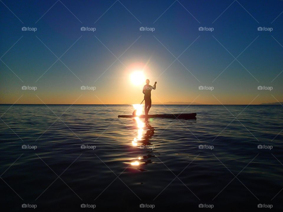 Girl paddle boarding during a beautiful sunrise in Mexico