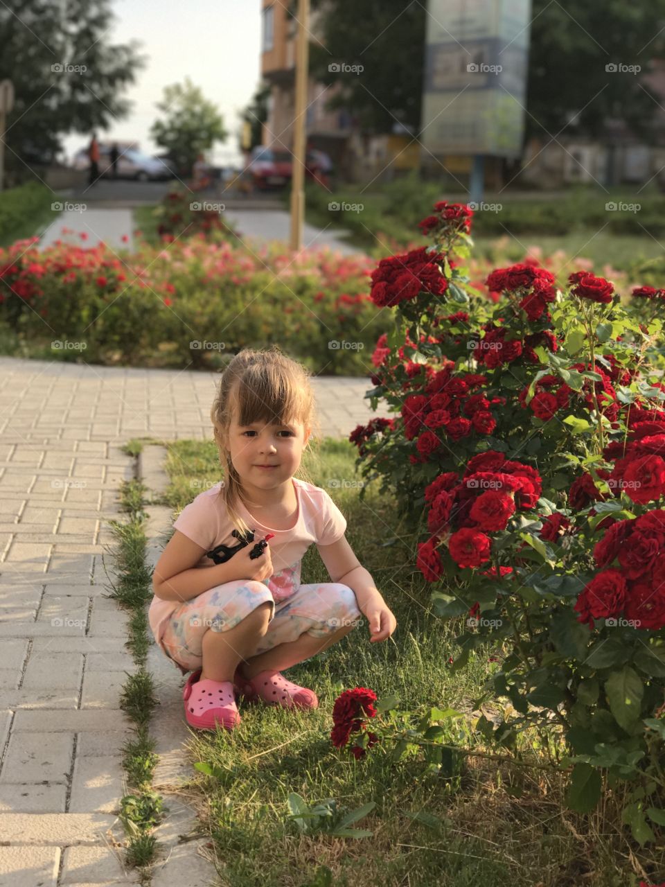 Little girl near rose flower plant at park