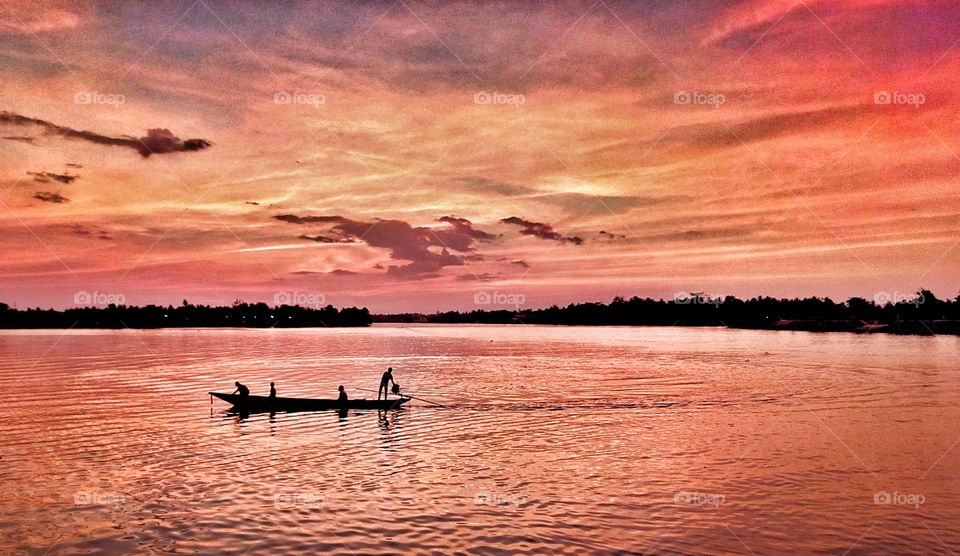 Fisherman with ship is coming back to home when sunset. Photo from river of Suratthani, Thailand.