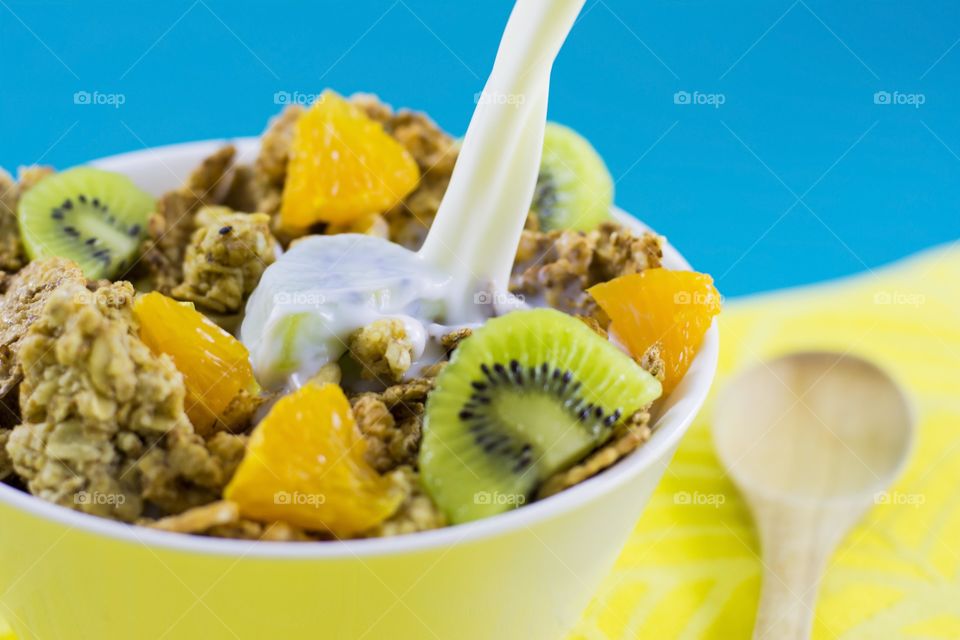 milk pouring into bowl full of cereals. milk pouring into bowl full of crunchy cereals and fruits