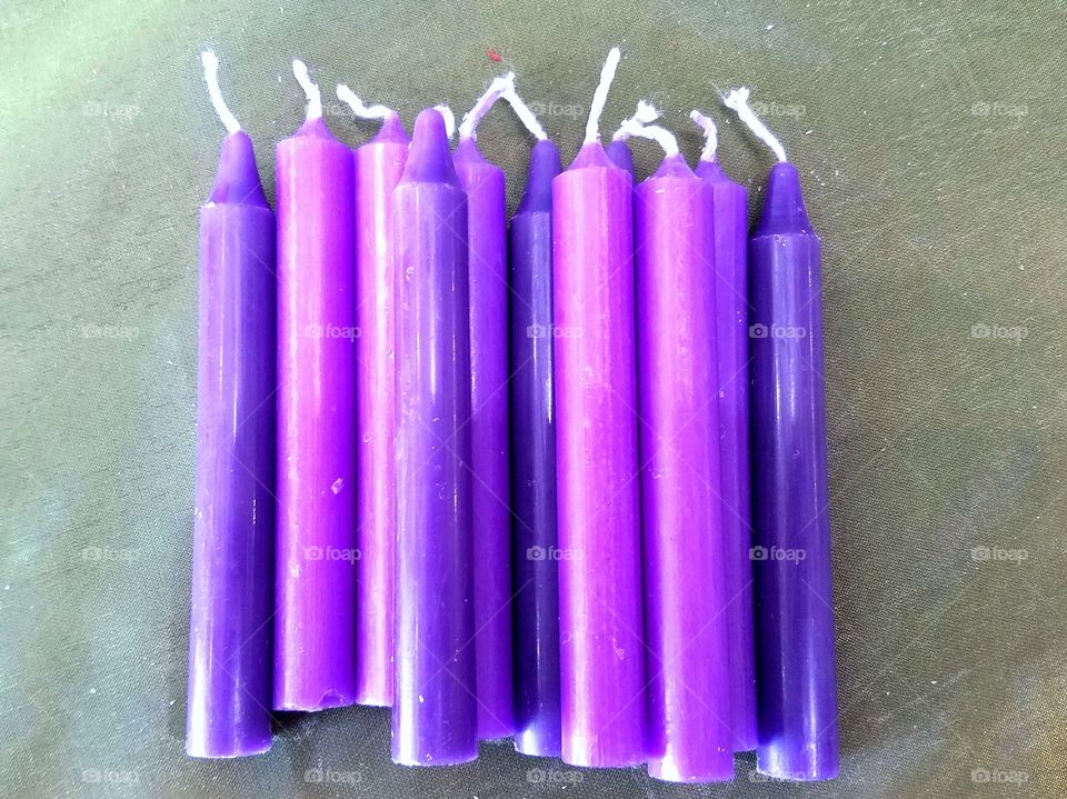 purple candles in a bunch on a moss green background