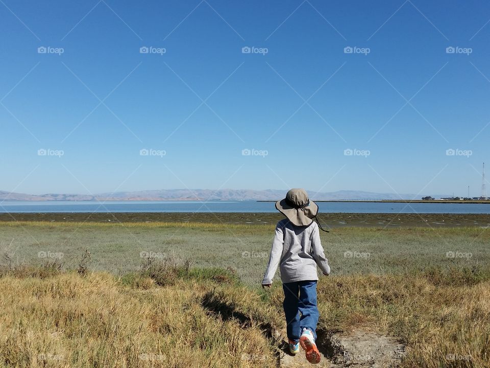 Young explorer. Boy walking towards the bay