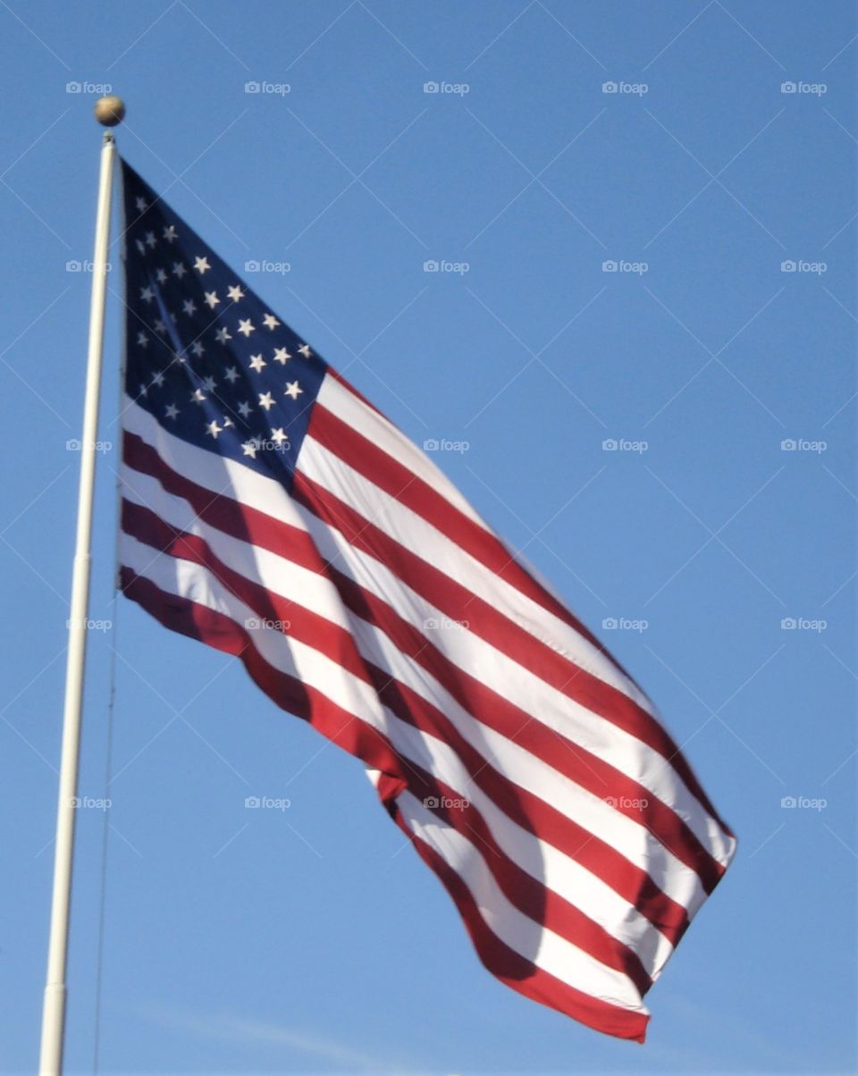 American flag waving in the bright sunshine in a blue sky