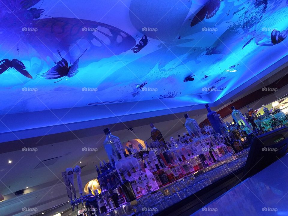 Colorful bar with butterflies and many bottles of liquor.