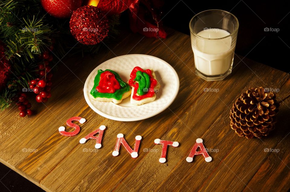Christmas Eve collage with plate of cookies, glass of milk and letters spelling Santa surrounded by seasonal decor
