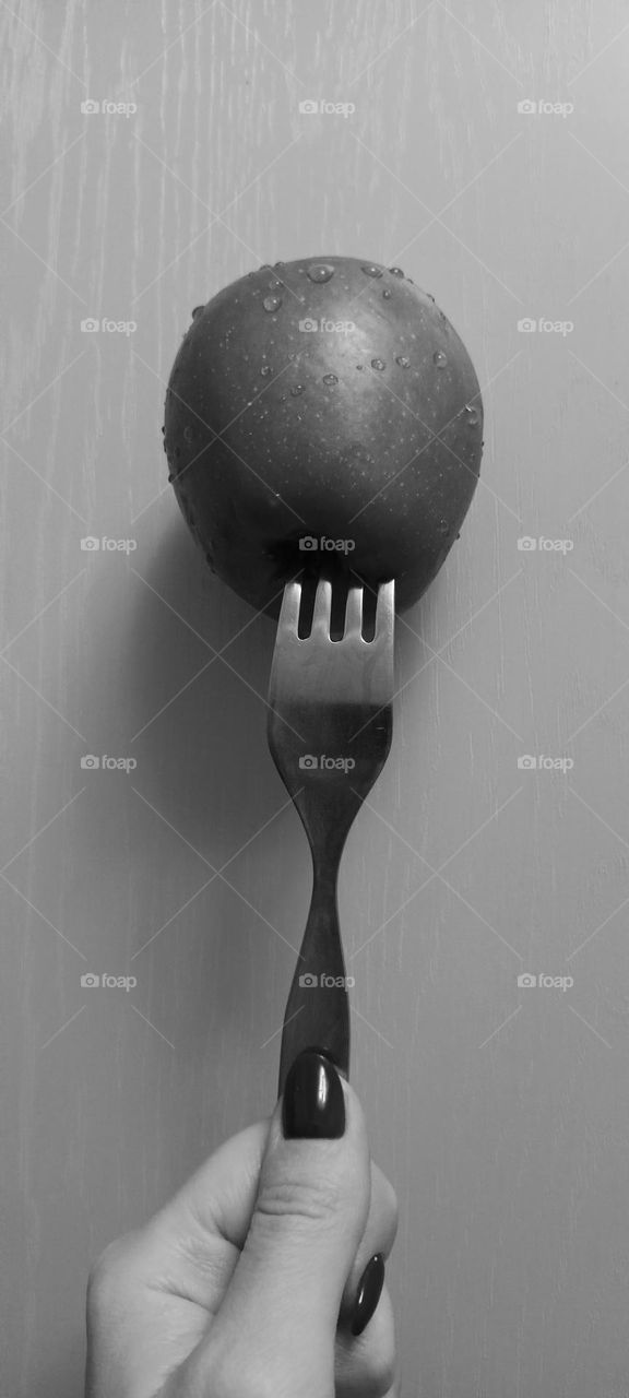 fork, apple, apple on the fork, water drops, the fork pierced the apple, black and white photo, a female hand holds a fork