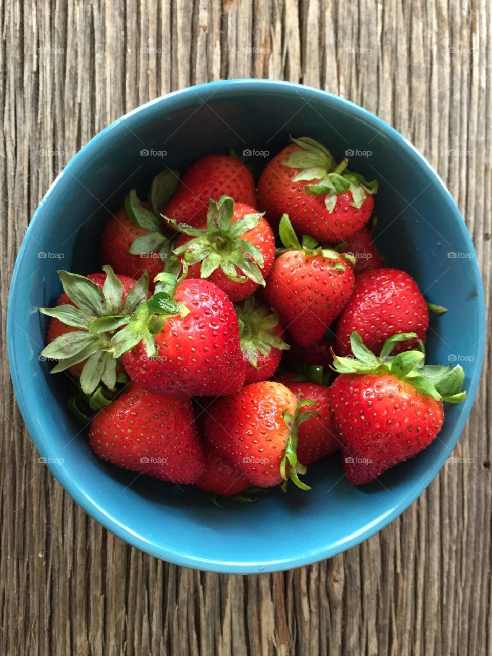 Fresh Summer Strawberries in blue bowl on distressed Barnwood 