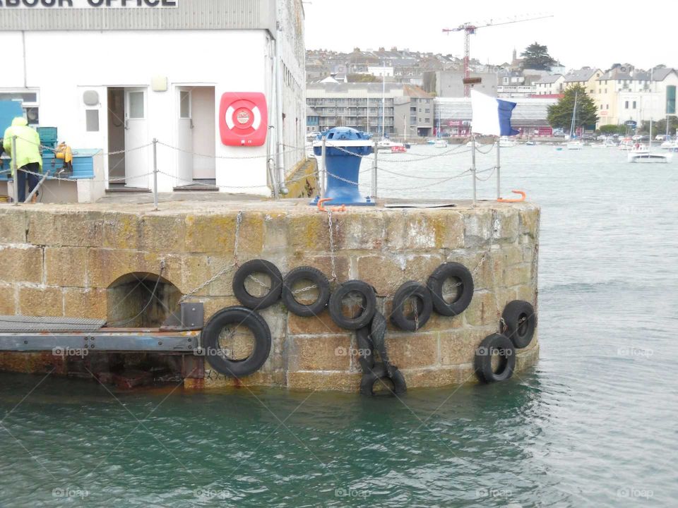 Penzance wet dock capstan and harbour wall covered in tires to protect the wall.